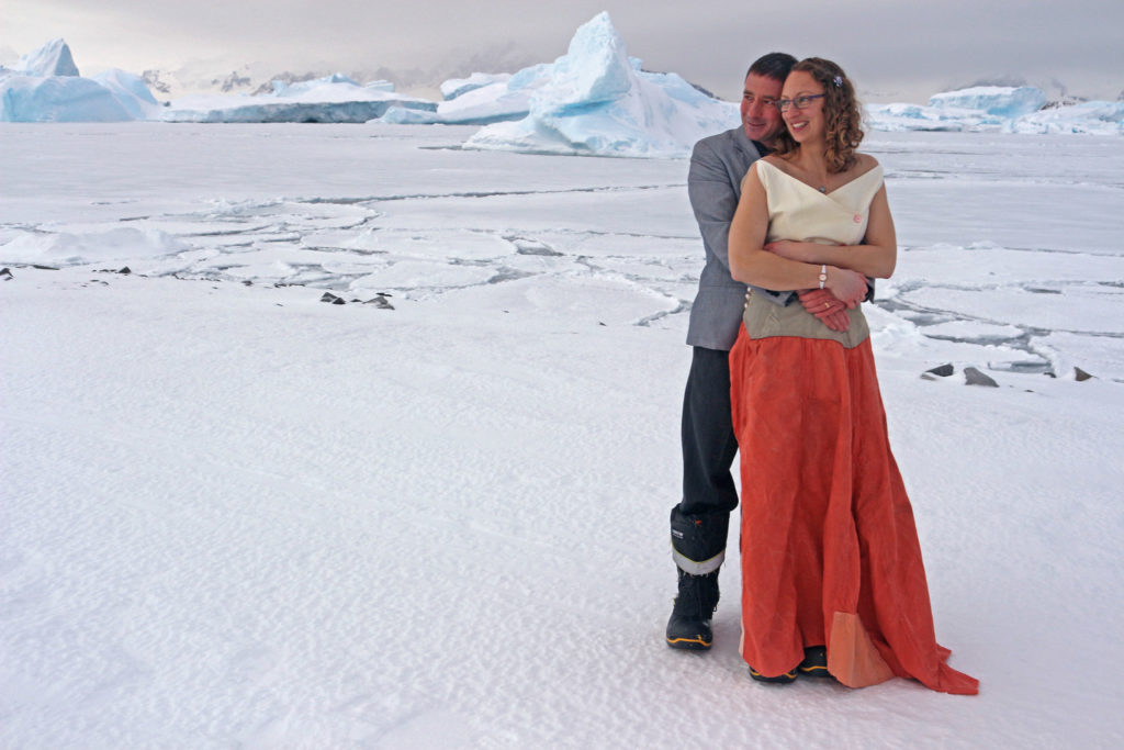 Couple embracing, standing on icy ground.